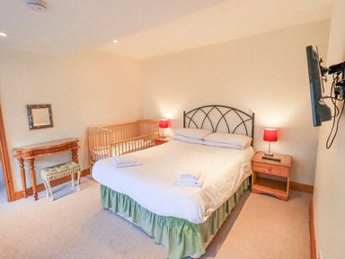 A bedroom with a bed, crib, and furniture at Ghyll Bank House Staveley near Windermere