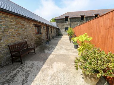 An outdoor path with a bench and planters at The Stall in Penuel near Llanmorlais