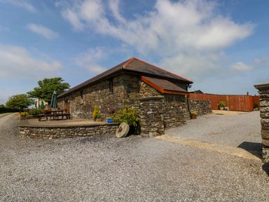 A stone building with outdoor tables and umbrellas at The Stall in Penuel near Llanmorlais