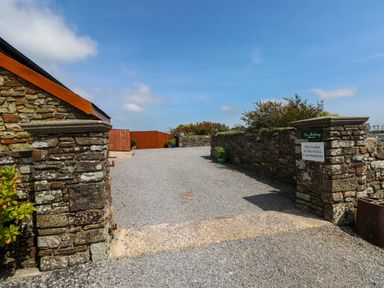 An outdoor parking area with a stone wall and gravel surface at The Stall in Penuel near Llanmorlais