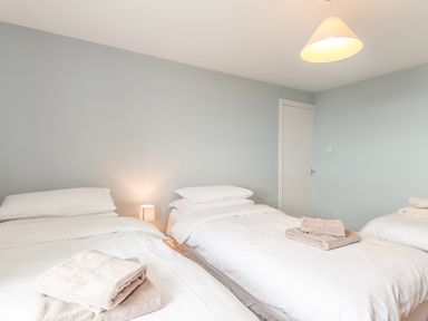 A bedroom with three single beds white bedding and folded towels on each bed at Coastguard Cottage Low Newton-by-the-Sea near Beadnell