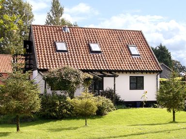 A small house with a tiled roof and skylights surrounded by trees and grass at The Hayloft in Necton near Swaffham