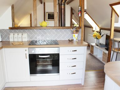 A kitchen with white cabinets an oven jars labeled tea coffee sugar biscuits and a yellow teapot at The Hayloft in Necton near Swaffham