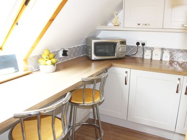 A kitchen corner with a microwave fruit bowl and storage jars at The Hayloft in Necton near Swaffham