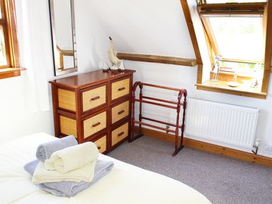 A bedroom corner with a chest of drawers a towel rack and a window at The Hayloft in Necton near Swaffham