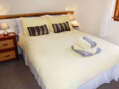 A bedroom with a double bed with yellow bedding striped pillows bedside tables with lamps and folded towels on the bed at The Hayloft in Necton near Swaffham