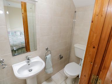 A bathroom with a white sink and mirror above it a toilet and a towel hanging on a ring at Quayside House in Roundstone County Galway