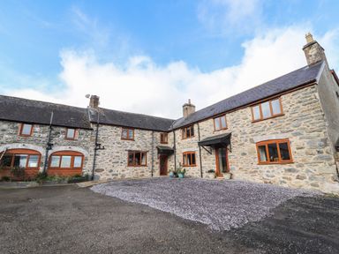 Stone farm house with multiple windows and slate roof with gravel courtyard at Maestyddyn Farm House in Clawddnewydd near Ruthin