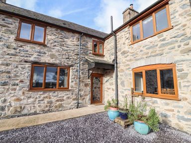 Stone exterior of a house with wooden framed windows a door and potted plants at Maestyddyn Farm House in Clawddnewydd near Ruthin