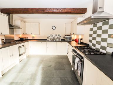 A kitchen with white cabinets gas stoves and checkered tile backsplash at Maestyddyn Farm House in Clawddnewydd near Ruthin