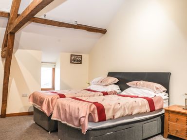 A bedroom with two single beds joined together and wooden beams on the ceiling at Maestyddyn Farm House Clawddnewydd near Ruthin