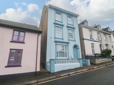 A street view of three attached houses with one blue house in the center at Dunholme House in Teignmouth