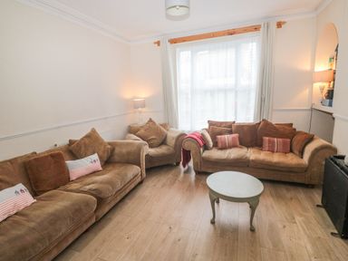 A living room with brown sofas a round coffee table and two lamps at Dunholme House in Teignmouth