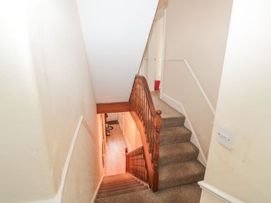 A carpeted staircase with wooden handrails in a narrow hallway at Dunholme House in Teignmouth