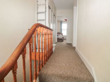 A carpeted hallway with a wooden handrail and a ladder leaning against the wall at Dunholme House in Teignmouth