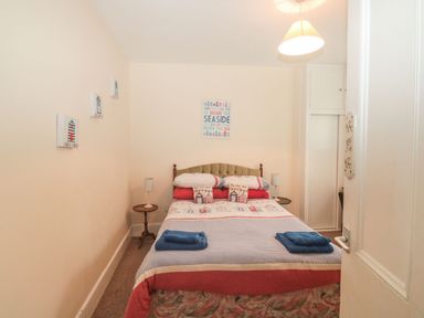 A bedroom with a bed two side tables with lamps and wall decorations at Dunholme House in Teignmouth