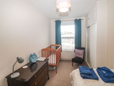 A bedroom with a crib dresser chair and bed with folded towels at Dunholme House in Teignmouth