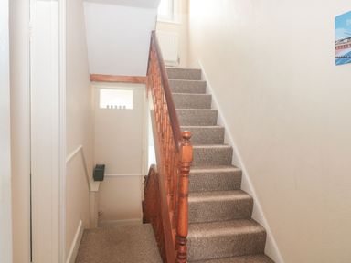 A carpeted staircase with wooden handrail and beige walls at Dunholme House in Teignmouth