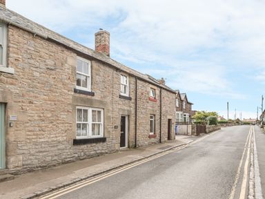 A street view with stone houses and a paved sidewalk at Fisherman's Cottage in Seahouses