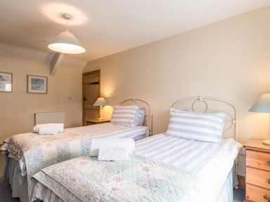 A bedroom with two single beds with striped bedding and bedside lamps at Fisherman's Cottage in Seahouses