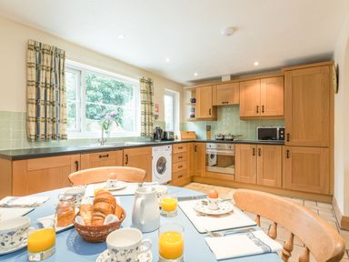 A kitchen with wooden cabinets and a table set for breakfast at Brians Cottage in Alnmouth