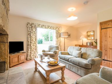 A living room with sofa armchairs coffee table television and wooden furniture at Brians Cottage in Alnmouth