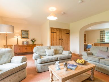A living room with sofas coffee table and lamps at Brians Cottage in Alnmouth