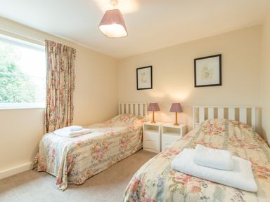 A bedroom with two single beds with floral bedspreads and towels on each bed at Brian's Cottage in Alnmouth