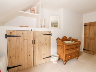 A room with wooden storage doors a wooden dresser a small trash bin and a wooden door at Manor Farm Cottage in Swaffham