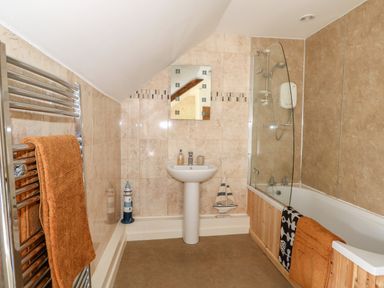 A bathroom with a sink mirror bathtub and towels at Manor Farm Cottage in Swaffham