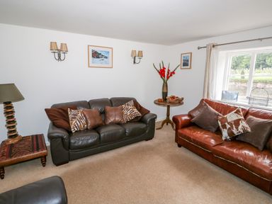 A living room with two sofas and pillows near a window and side tables at Manor Farm Cottage in Swaffham