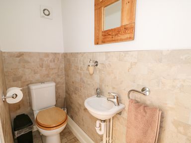 A small bathroom with a toilet a sink a towel on a rack and a mirror at Manor Farm Cottage in Swaffham