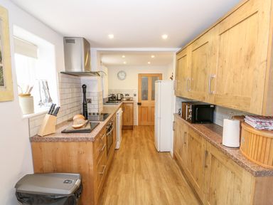 A kitchen with wooden cabinets and a countertop with bread and knives at Manor Farm Cottage in Swaffham