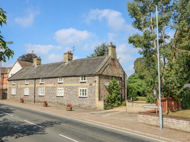 A street view of a row of stone cottages with chimneys and small windows on Mangate Street at Manor Farm Cottage in Swaffham