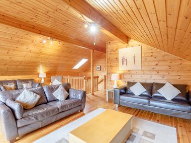 A living room with two black leather sofas a wooden coffee table and wooden walls and ceiling at Jamaal Lodge South Broomhill near Amble
