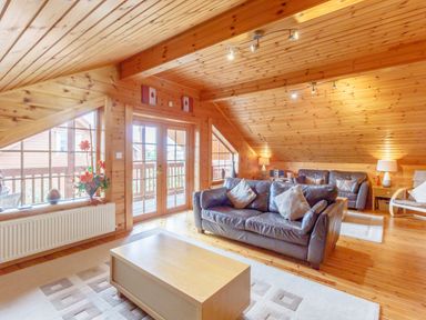 A living room with leather sofas wooden coffee table and flowers on a window sill at Jamaal Lodge South Broomhill near Amble