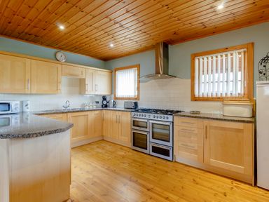 A kitchen with wooden cabinets wooden ceiling wooden floor and appliances at Jamaal Lodge South Broomhill near Amble