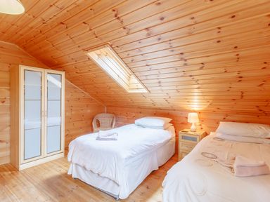 A bedroom with two single beds a bedside table with a lamp a wardrobe and a skylight ceiling window at Jamaal Lodge South Broomhill near Amble