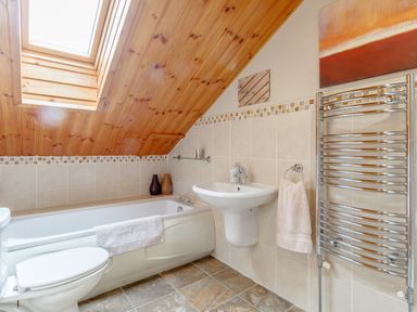 A bathroom with a bathtub toilet sink towel rail and skylight at Jamaal Lodge in South Broomhill near Amble