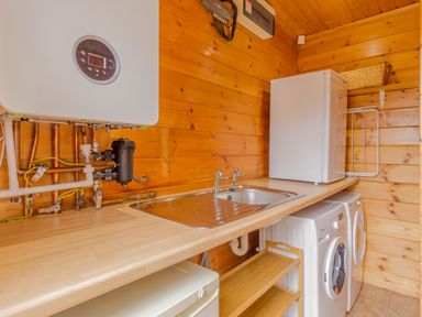 A utility room with a sink washing machine dryer and a small refrigerator at Jamaal Lodge in South Broomhill near Amble