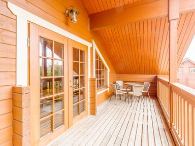 A wooden balcony with a round table and four chairs at Jamaal Lodge in South Broomhill near Amble