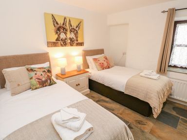 A bedroom with two single beds and animal pillows at Potters Barn in Begelly near Kilgetty