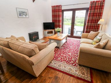 A living room with two sofas a coffee table and a television at Potters Barn in Begelly near Kilgetty