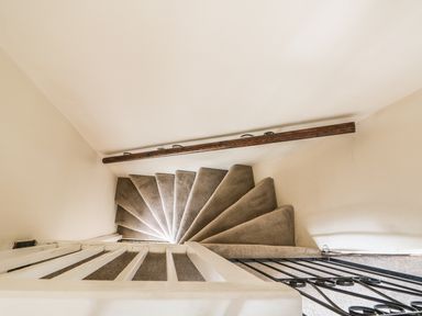 A spiral staircase with carpeted steps and a wooden handrail at Megs Cottage in Norwich