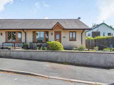 A single-story house with brown framed windows a brown door and a low concrete wall at Gorwel in Llan Ffestiniog near Blaenau Ffestiniog