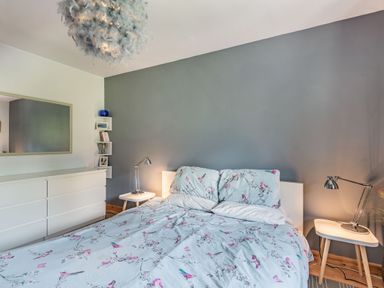 A bedroom with a bed covered in floral patterned bedding two side tables with lamps a white dresser and a large mirror at Gorwel in Llan Ffestiniog near Blaenau Ffestiniog