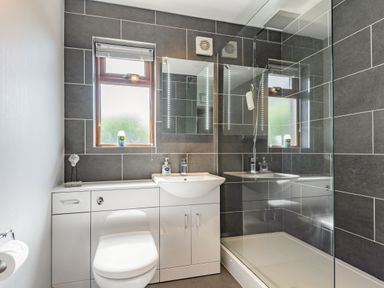 A bathroom with a toilet, sink, mirror, window, and shower at Gorwel in Llan Ffestiniog near Blaenau Ffestiniog