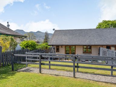 A garden with a gravel path and wooden fences outside a house with a slate roof at Gorwel in Llan Ffestiniog near Blaenau Ffestiniog