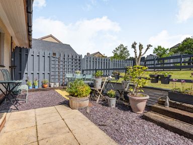 An outdoor patio area with potted plants tables chairs and a gray wooden fence at Gorwel in Llan Ffestiniog near Blaenau Ffestiniog
