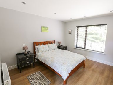 A bedroom with a wooden bed and two bedside tables with lamps at The Visiting House in Gorteen near Dunmore County Galway